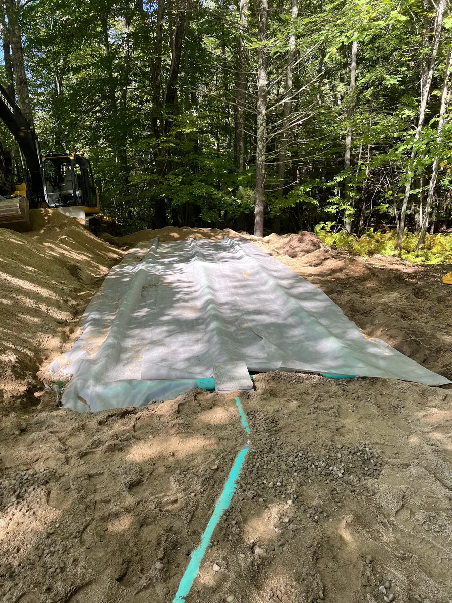 Insulated septic lines in an open trench beside a home