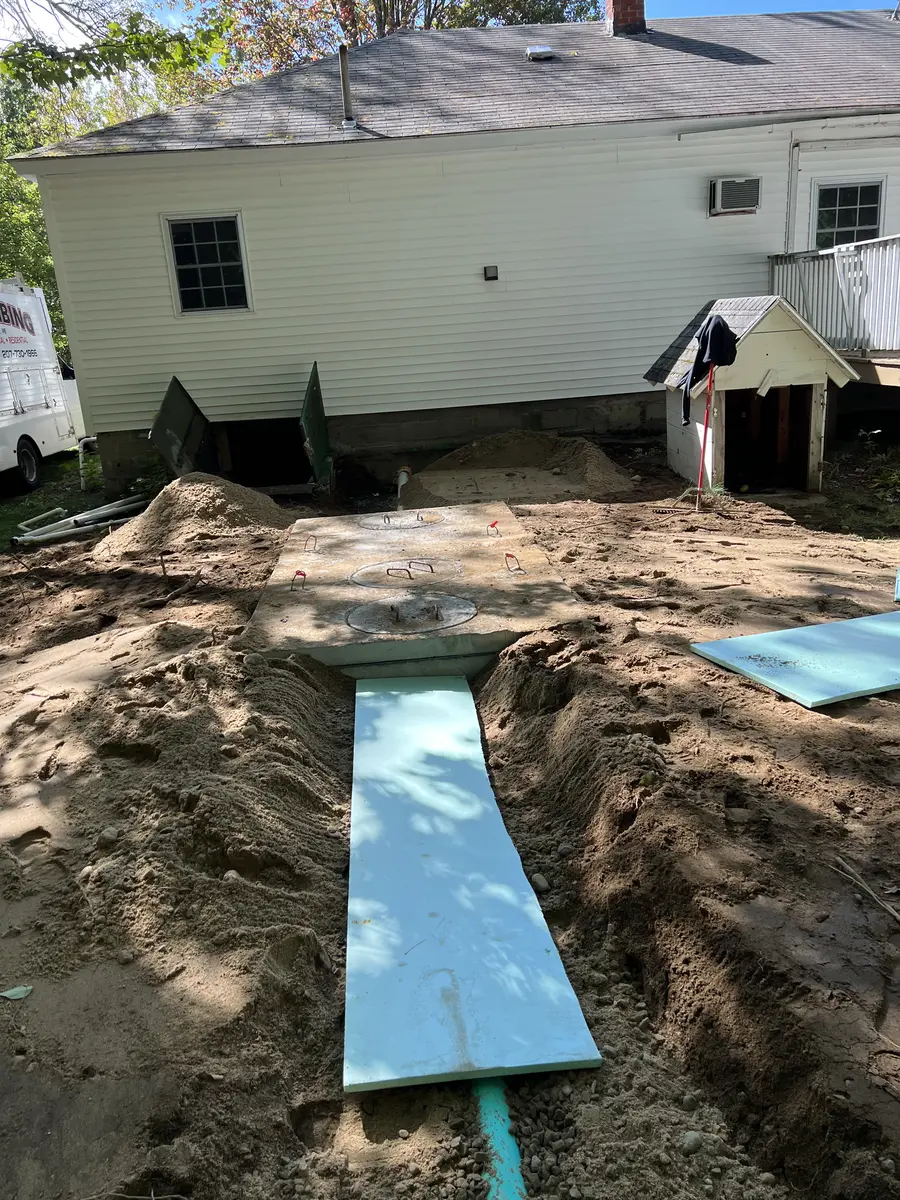 Foam insulation board being placed over septic lines in a trench
