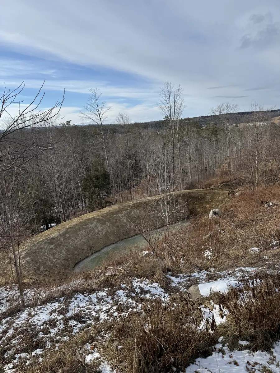 Newly excavated pond holding water on a cleared rise