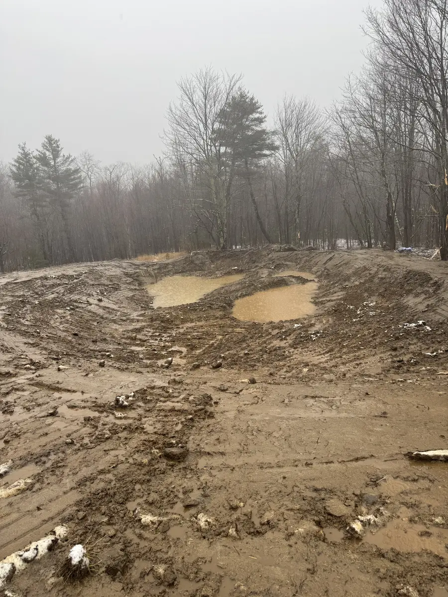 Freshly shaped pond basin collecting water after excavation