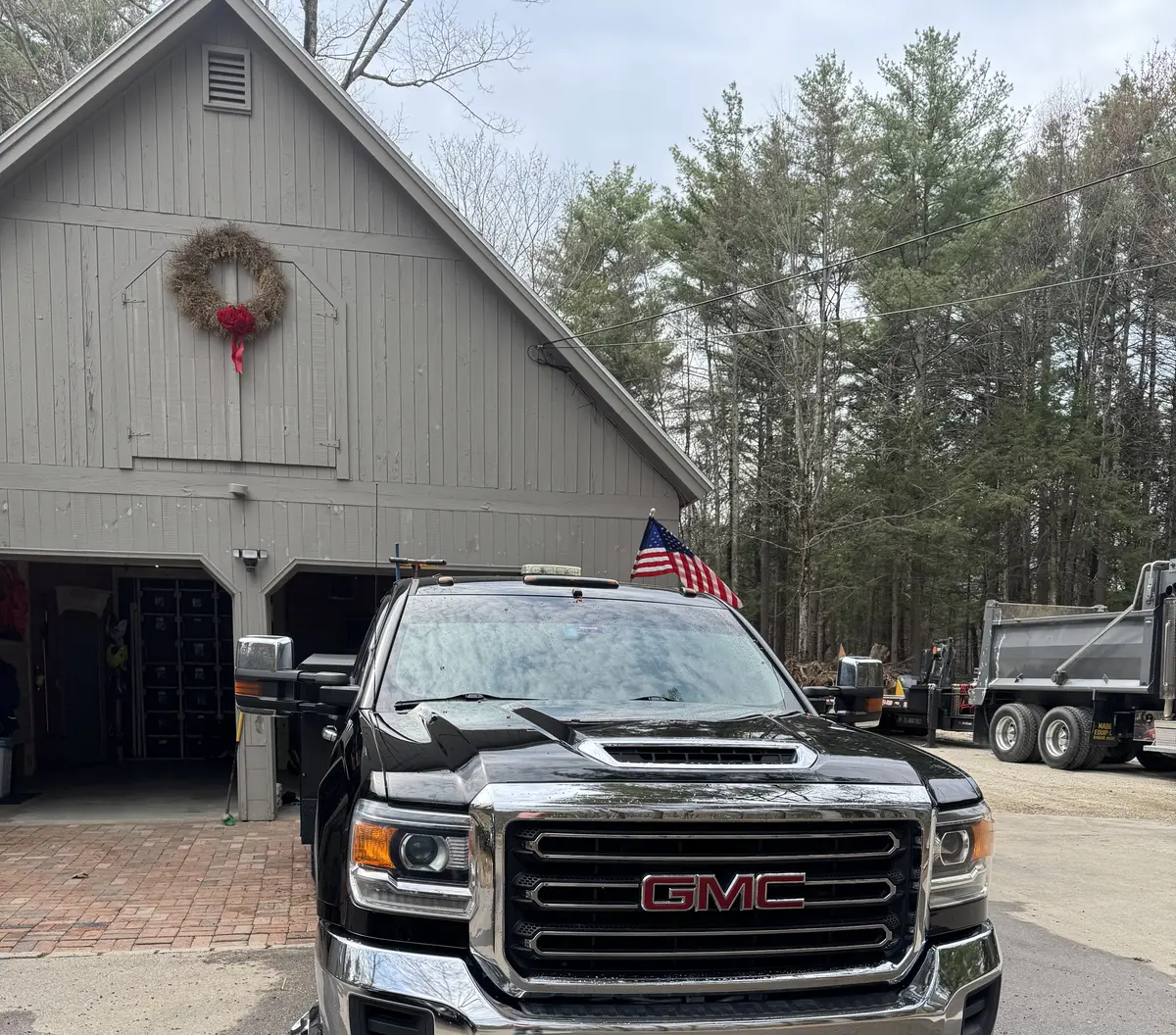 Black heavy-duty plow truck parked at the shop on a winter morning
