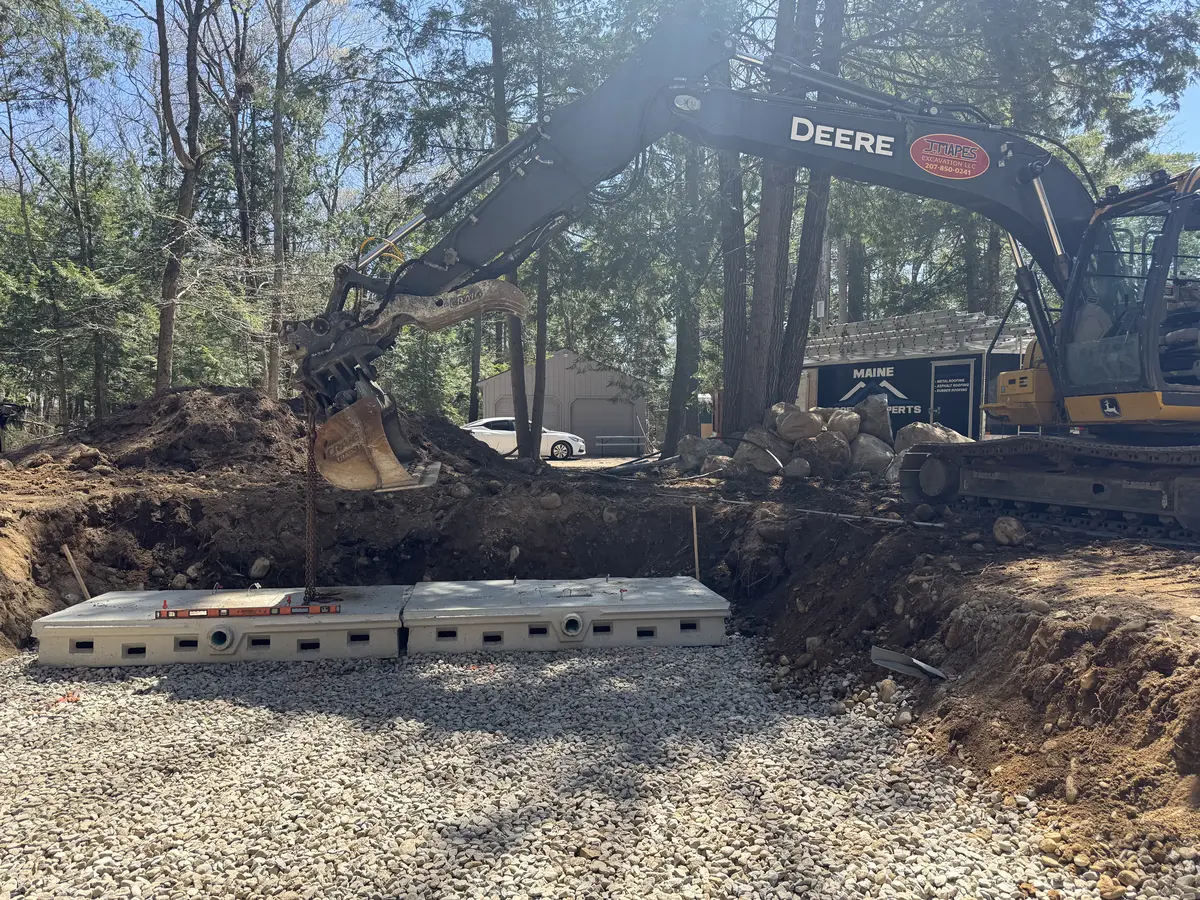 Excavator setting precast concrete septic tanks on a residential lot