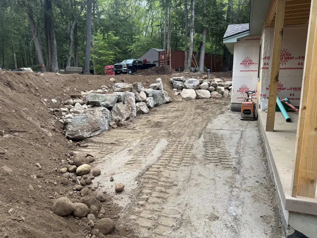 Boulder retaining walls and graded drive at a new home under construction