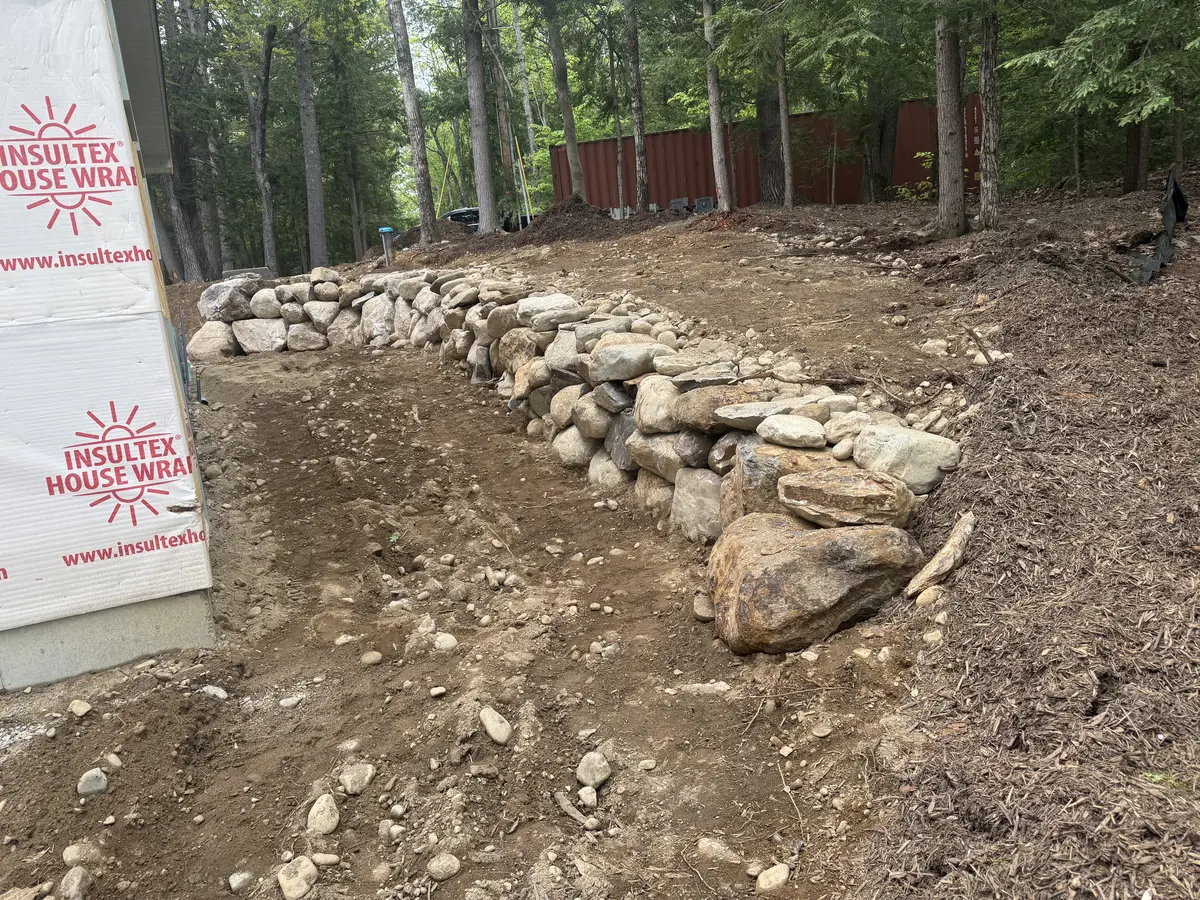 Stone retaining wall following a graded path at a new build
