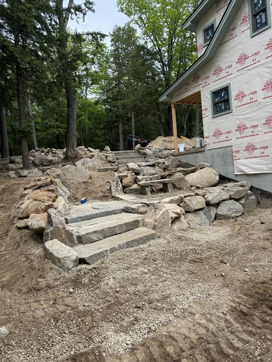 Stone steps and wall taking shape beside a home under construction