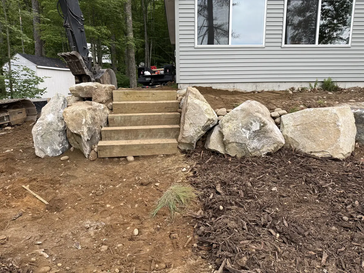 New timber steps set between machine-placed boulders at a home entry