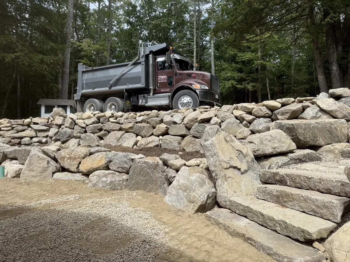 J. Mapes Excavation dump truck above a fieldstone retaining wall in progress