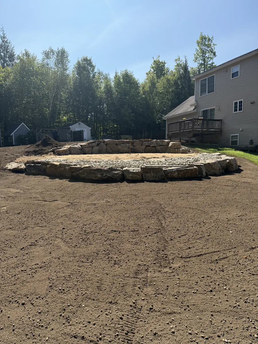 Circular stone fire pit area built into a graded backyard