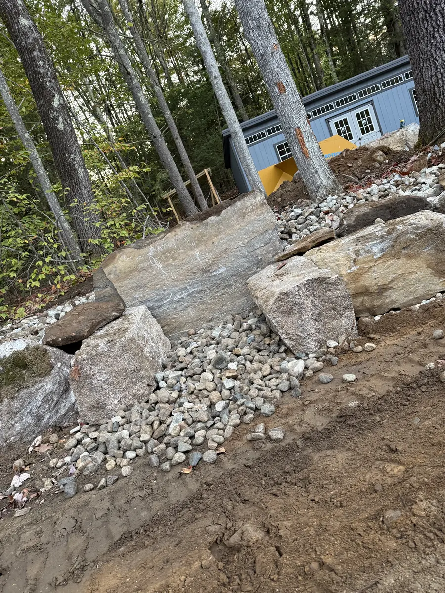 Granite blocks and drainage stone staged for a wall build