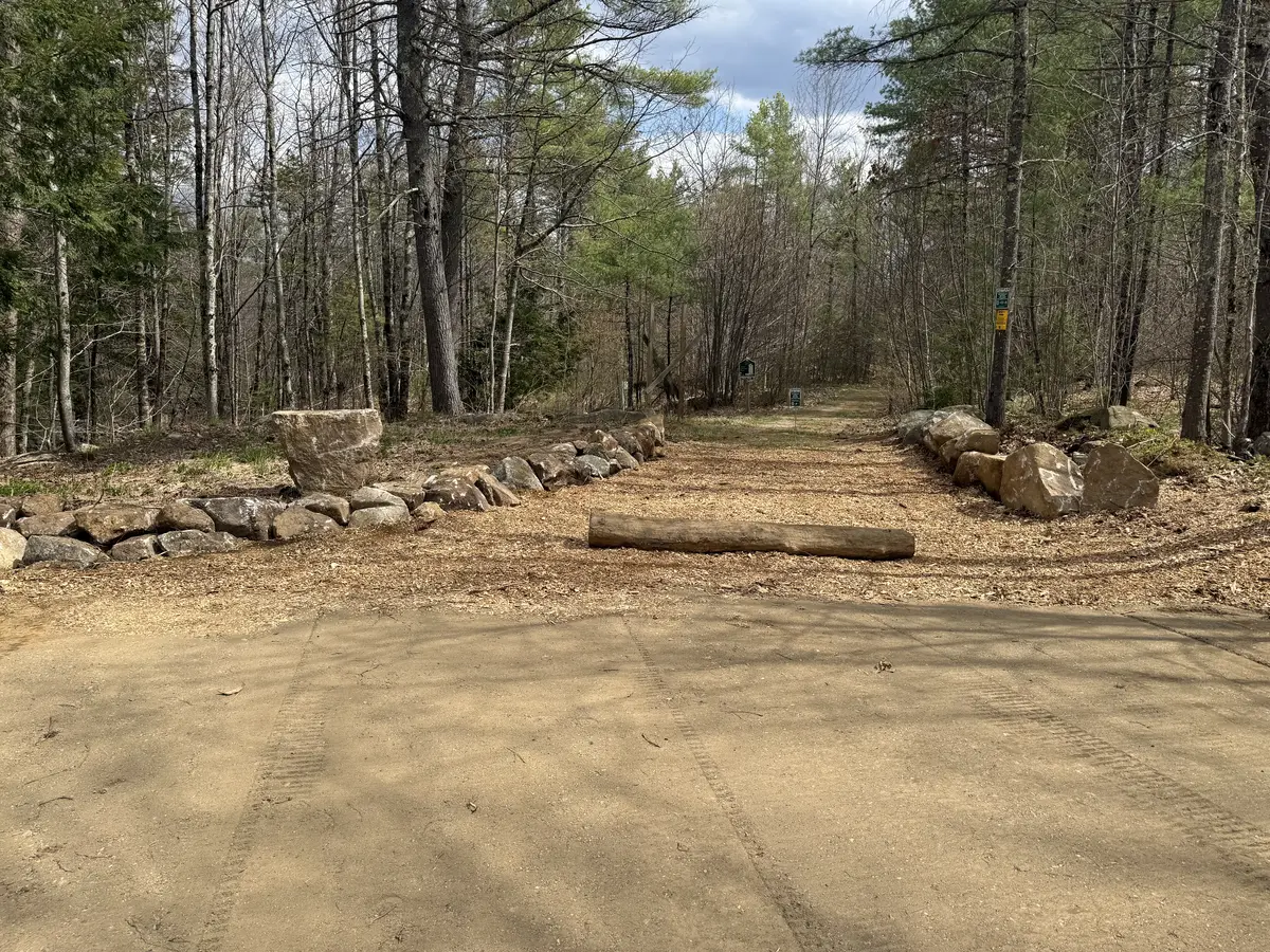 Wide graded gravel pad and drive on a cleared wooded lot