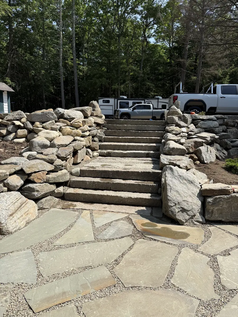 Wide granite slab staircase climbing through a boulder retaining wall