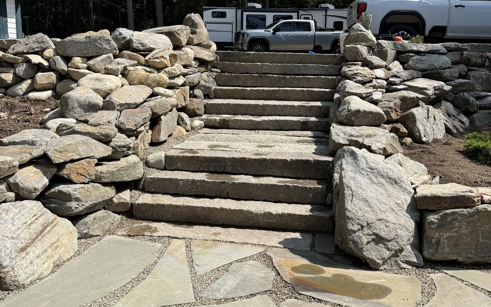 Wide granite slab staircase climbing through a boulder retaining wall